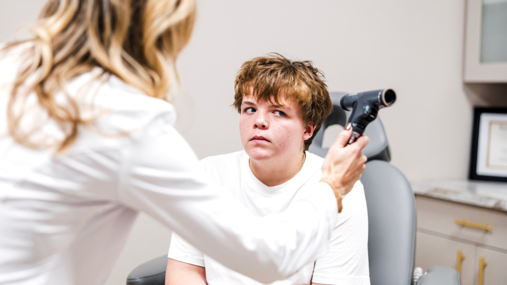 Provider examining a teen boy's head during a headache evaluation.