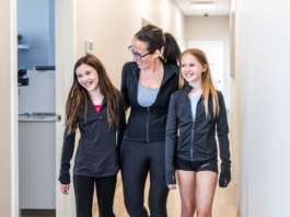 Mom walking with her two daughters through Transcend Headache Clinic after fall sports practice.