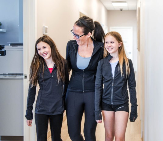 Mom walking with her two daughters through Transcend Headache Clinic after fall sports practice.