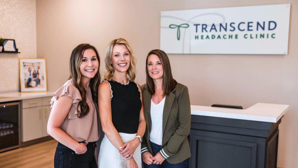 Headache specialists standing in front of the Transcend Headache Clinic sign.